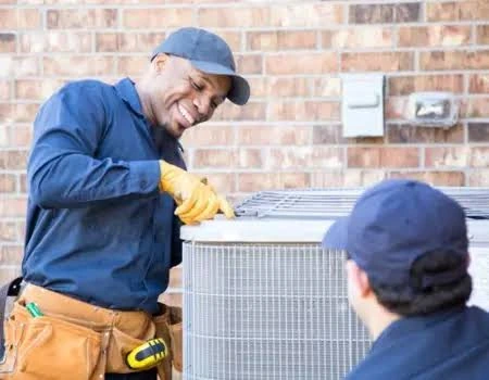HVAC technicians inspecting the top of an outdoor condenser