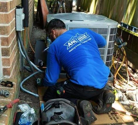 Technician repairing an outdoor air conditioner beside a brick wall