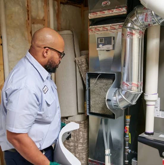 Technician inspecting an indoor furnace and connected ductwork