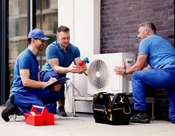 Three HVAC technicians discussing an outdoor system